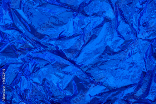 Monochrome blue crumpled, creased iridescent metal foil texture. Abstract colored background.