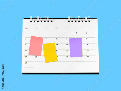 three colourful sticky notes attached on desk calendar page isolated on blue