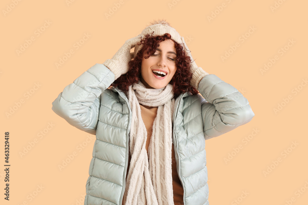 Happy woman adjusting knitted hat on color background Happy woman adjusting knitted hat on color background