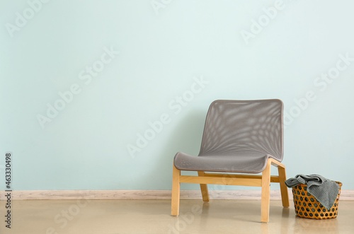 Modern armchair with basket near color wall