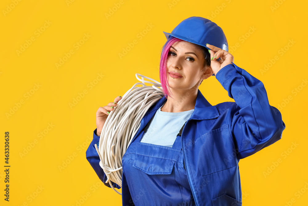 Female electrician with cables on color background