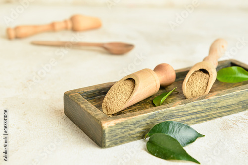Wooden board and scoops with hojicha powder on light background