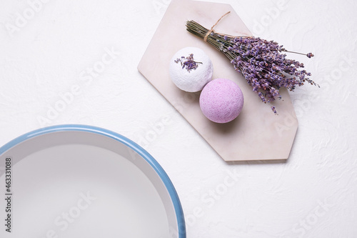 Bath bombs, lavender flowers and bowl with water on light background, closeup