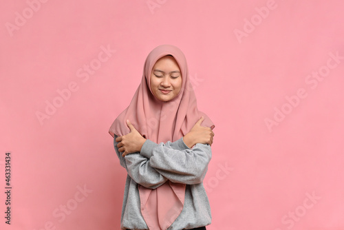 Young pretty muslim woman feeling in love, smiling, cuddling and hugging self, staying single © Heru