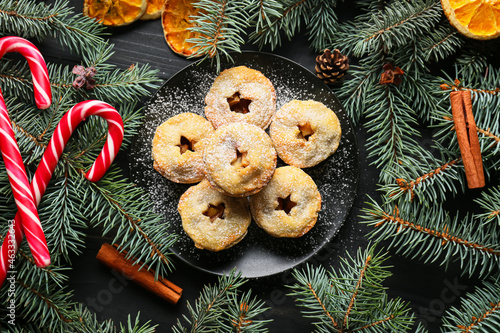 Plate with tasty mince pies and Christmas decor on dark background