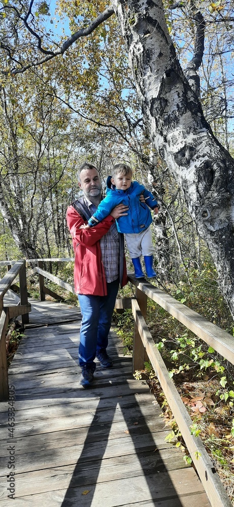 Father and son walk in the park. Happy family. Ecological trail. Sunny day.