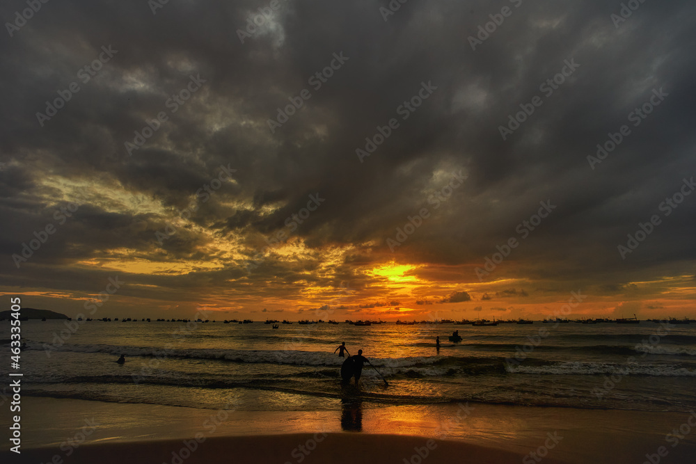 Surfers in the water surfing on a beautiful golden sunrise at the beach. Body board and surf lifestyle concept.