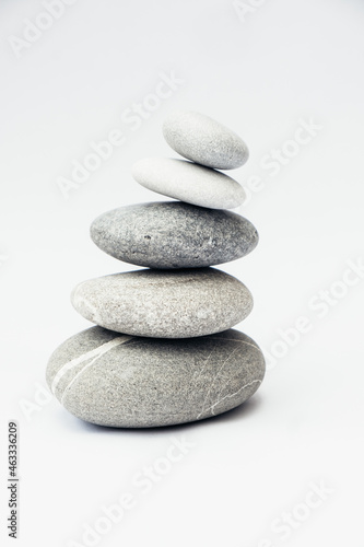 Stone cairn on light background, stones tower, simple poise stones. Purity harmony and Balance Concept. Vertical photo.