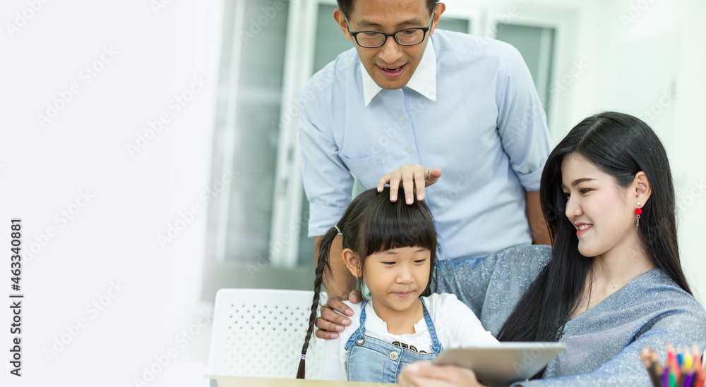 Father and mother are teaching their daughter using a digital tablet at home, Teach children how to use the internet safely, Internet safety for children and families concept. Father and mother are teaching their daughter using a digital tablet at home, Teach children how to use the internet safely, Internet safety for children and families concept.