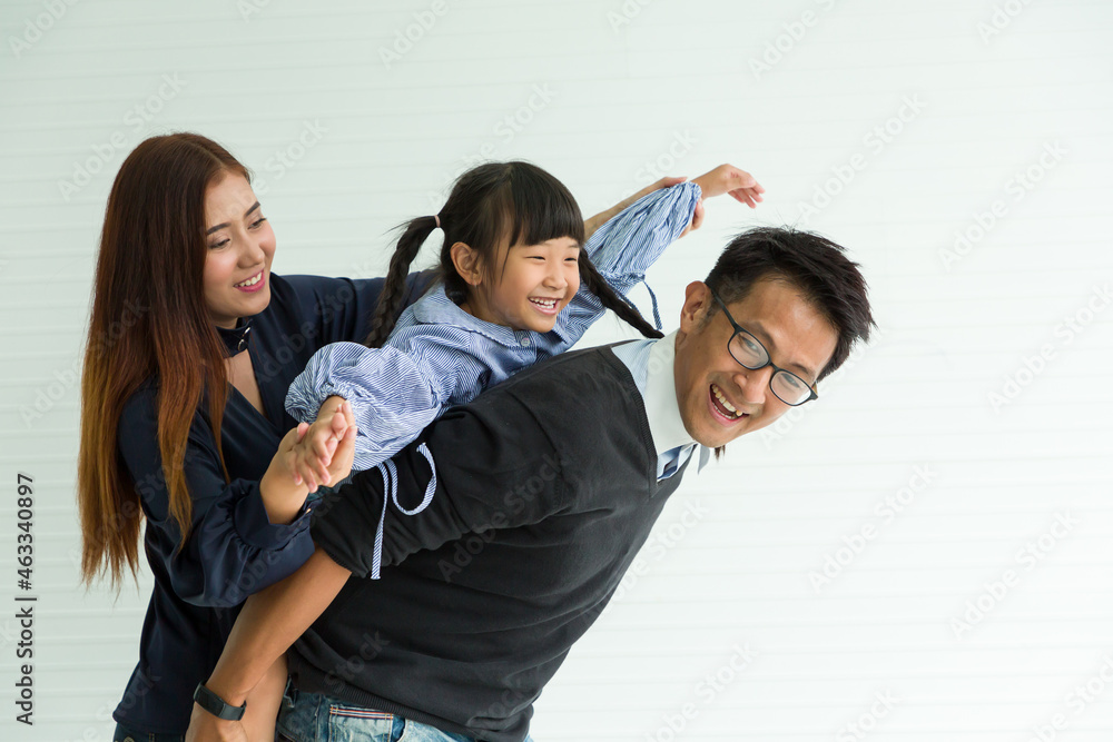 Happy Asian family having fun with home. Asian father playing and carrying little daughter on back at home with happy and smile Happy Asian family having fun with home. Asian father playing and carrying little daughter on back at home with happy and smile