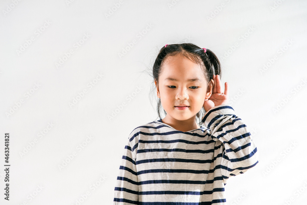 Happy Positive cute Asian little toddler kid girl holding ear with hand listening to a hearing for rumor or gossip. Over white background for text copy and space. Deafness concept Happy Positive cute Asian little toddler kid girl holding ear with hand listening to a hearing for rumor or gossip. Over white background for text copy and space. Deafness concept