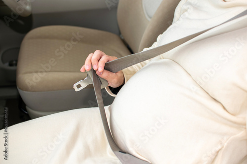 A young pregnant Asian woman wears a seatbelt appropriately and gets ready to visit a hospital