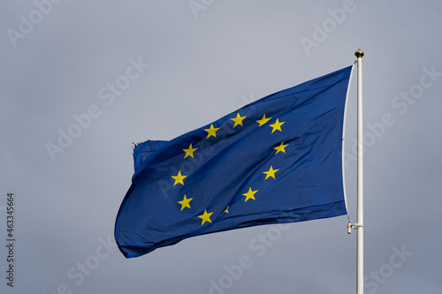 Flag of the European Union waving in the wind on flagpole in slow motion on cloudy sky background