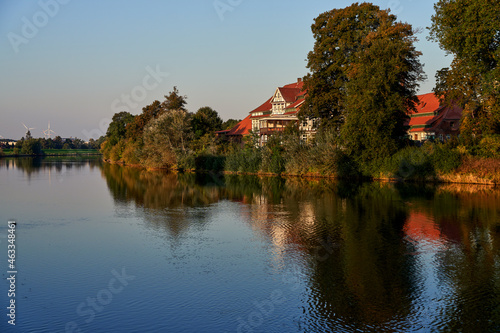 historical manor house in traditional half-timbered construction called "Rittergut von Behr" at the shore of the river Weser in Hoya (Germany) in scenic evening sunlight