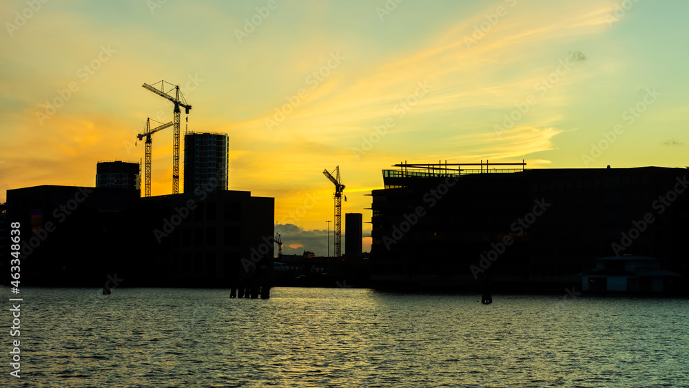 Tower construction cranes and buildings at sunset. Construction and real estate Copenhagen. Denmark.