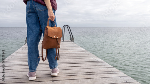 Foto Young girl with a backpack, looks at the sea, on a wooden pier