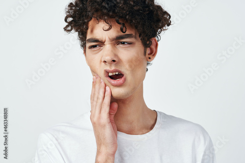 guy in white t-shirt with curly hair pain in the teeth health problems