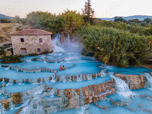 natural spa with waterfalls and hot springs at Saturnia thermal baths, Grosseto, Tuscany, Italy,Hot springs Cascate del Mulino man and woman in hot spring taking a dip during morning with fog photo