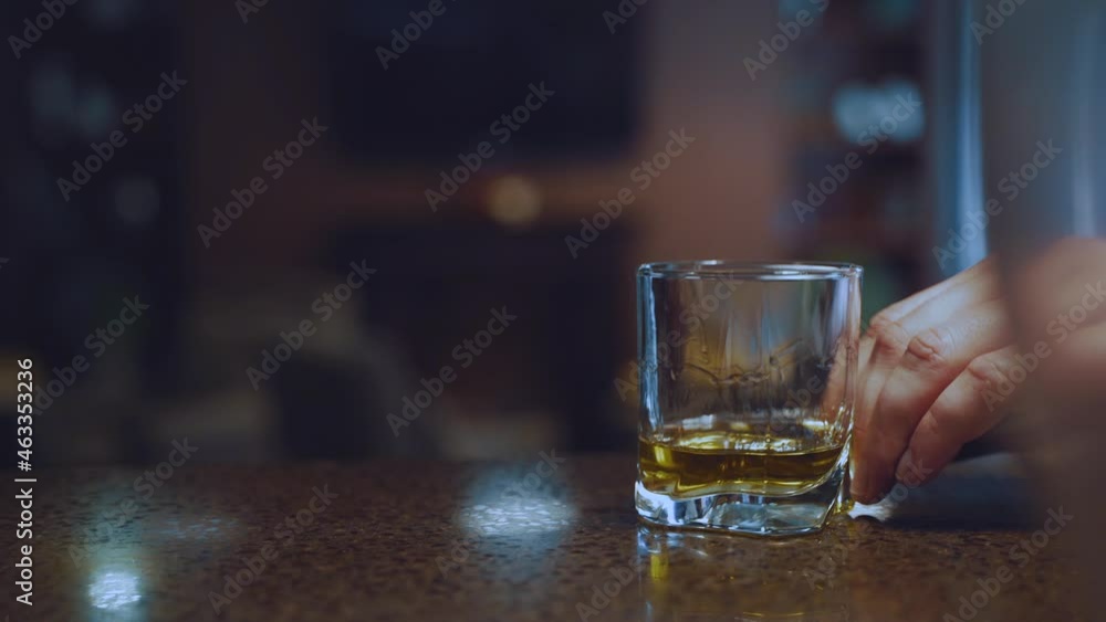 A glass of whiskey slides on the bar from one hand to the other A glass of whiskey slides on the bar from one hand to the other
