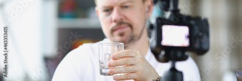 Video blogger drinks alcohol alone in front of camera photo