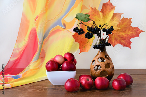 beautiful autumn bouquet of orange maple leaves  chokeberry and red apples on wooden table. Colorful nature. Harvest time
