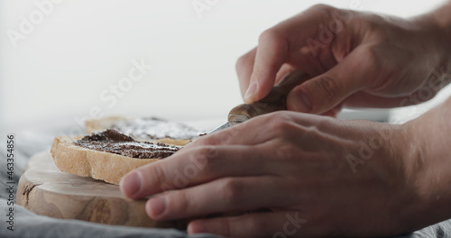 man spread chocolate nut cream on ciabatta slice