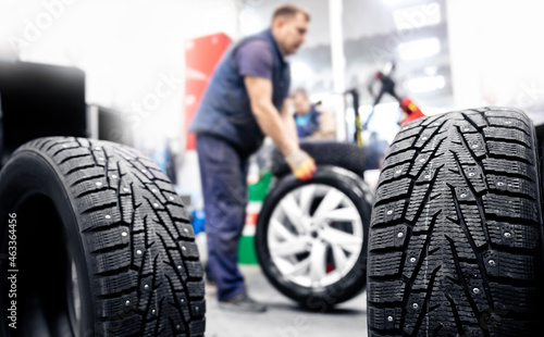 Concept car service replacement of winter and summer tires. Mechanic holding wheels at garage