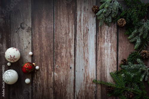 christmas decoration with christmas balls, green branches and pine cones on a rustic, old, wooden background, vintage style