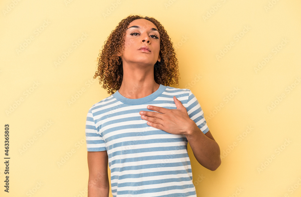 Young latin transsexual woman isolated on yellow background taking an oath, putting hand on chest. - obrazy, fototapety, plakaty 