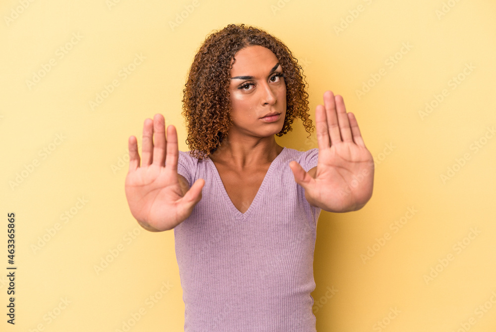 Young latin transsexual woman isolated on yellow background standing with outstretched hand showing stop sign, preventing you. Young latin transsexual woman isolated on yellow background standing with outstretched hand showing stop sign, preventing you.