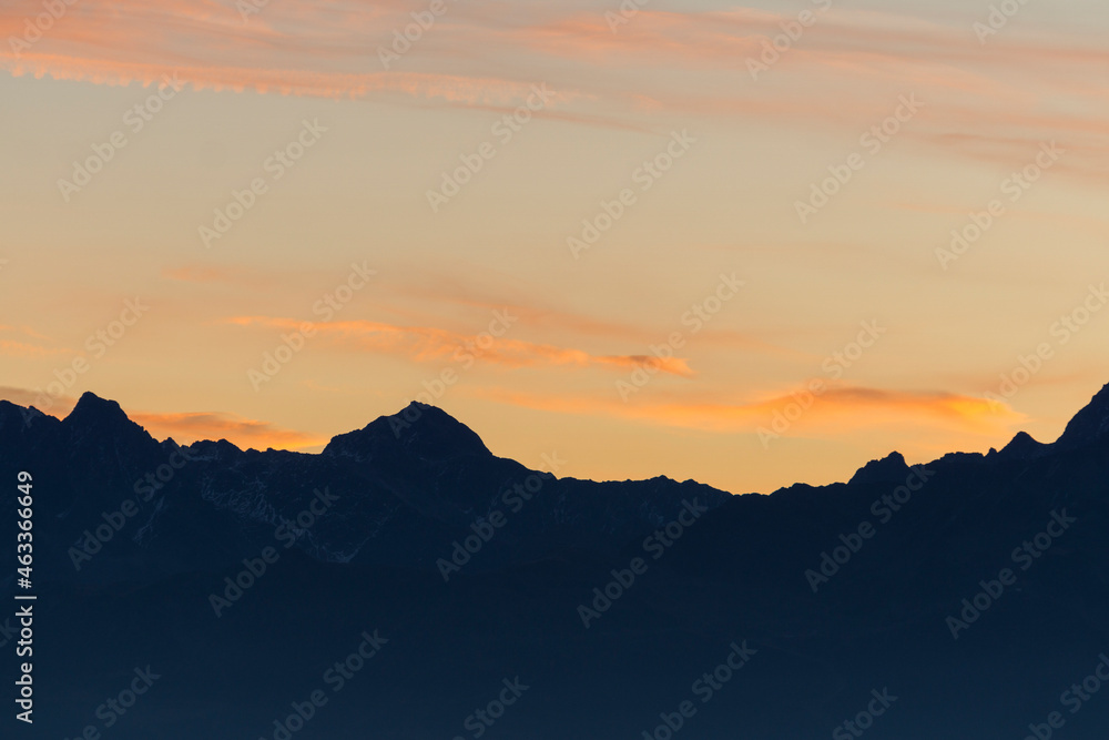 Orange clouds and mountain silhouettes at sunrise