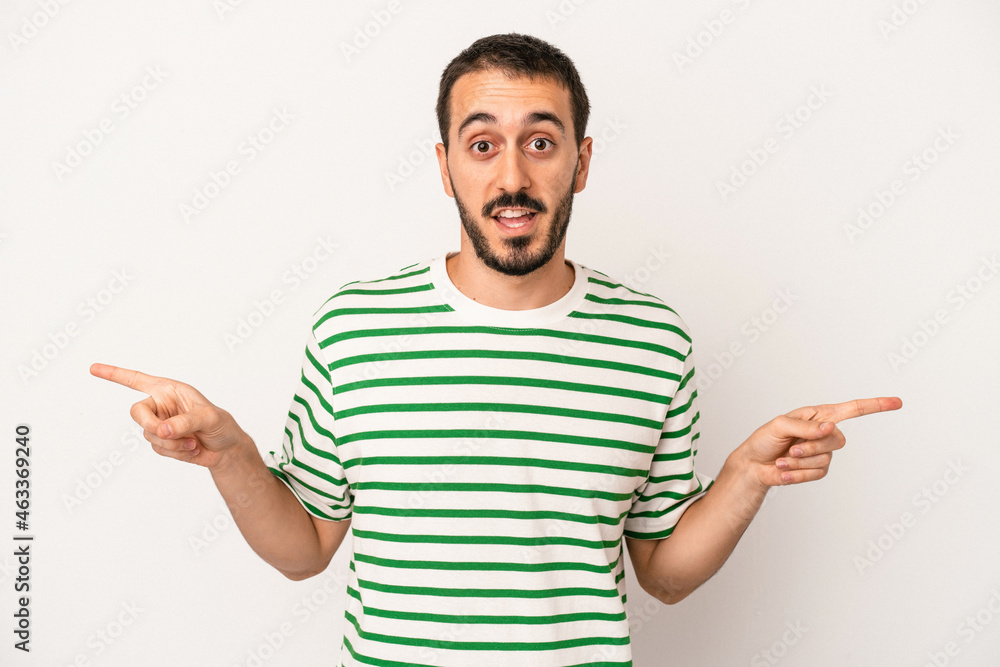 Young caucasian man isolated on white background pointing to different copy spaces, choosing one of them, showing with finger. Young caucasian man isolated on white background pointing to different copy spaces, choosing one of them, showing with finger.