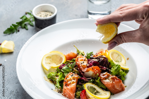 Fish salad salmon, lettuce greens and lemon. splashes of lemon juice, Food recipe background. Close up