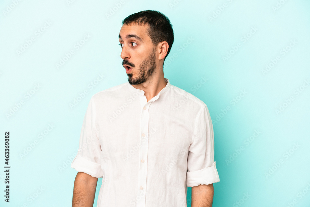Young caucasian man isolated on blue background being shocked because of something she has seen. Young caucasian man isolated on blue background being shocked because of something she has seen.