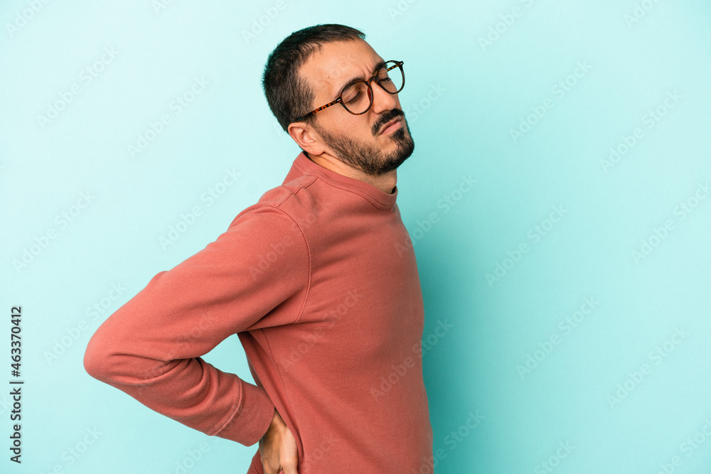 Young caucasian man isolated on blue background suffering a back pain. Young caucasian man isolated on blue background suffering a back pain.