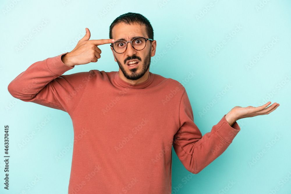 Young caucasian man isolated on blue background holding and showing a product on hand. Young caucasian man isolated on blue background holding and showing a product on hand.