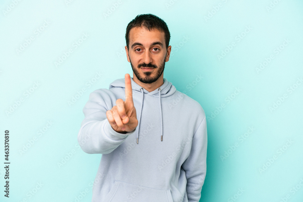 Young caucasian man isolated on blue background showing number one with finger.