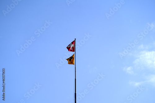 Swiss flag and flag of Canton Schaffhausen blowing in the wind at Village of Neuhausen am Rheinfall. Photo taken September 25th, 2021, Neuhausen am Rheinfall, Switzerland.