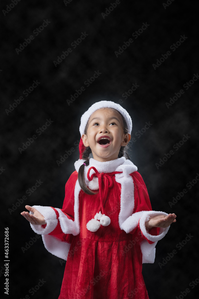 A girl wearing a Santa Claus costume and a black background. A girl wearing a Santa Claus costume and a black background.