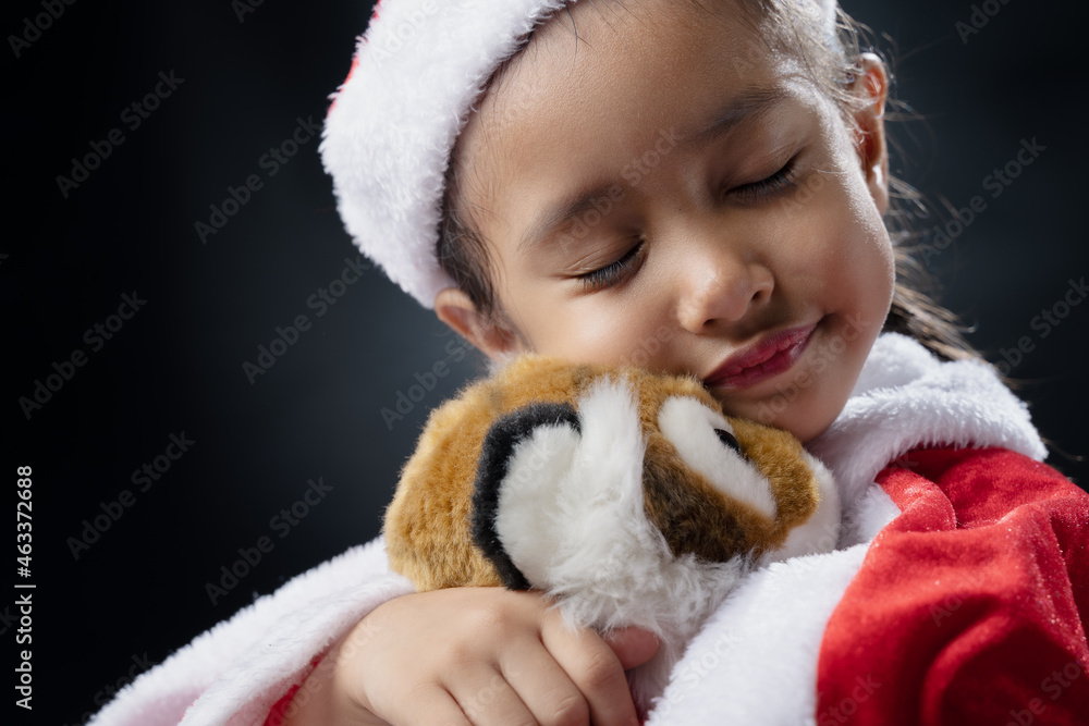 A girl wearing a Santa Claus costume and a black background.