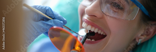 Doctor dentist treating teeth using LED curing light machine in clinic closeup