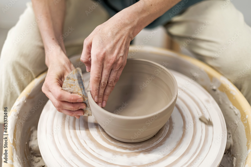 Hands of young woman working on pottery wheel in cozy workshop and making vase or mug - obrazy, fototapety, plakaty 