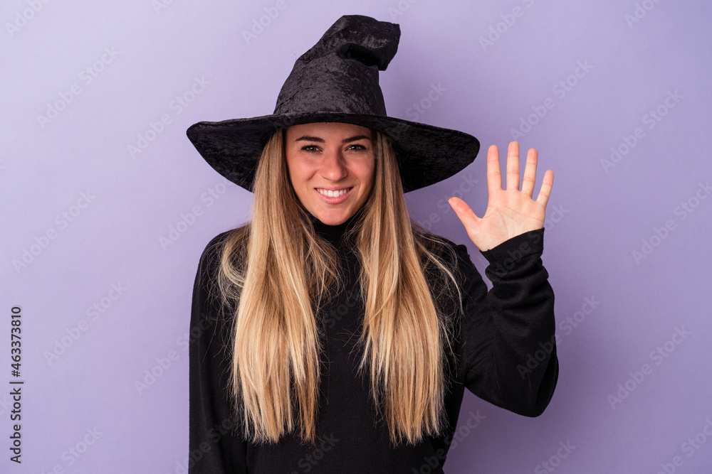 Young Russian woman disguised as a witch celebrating Halloween isolated on purple background smiling cheerful showing number five with fingers. Young Russian woman disguised as a witch celebrating Halloween isolated on purple background smiling cheerful showing number five with fingers.