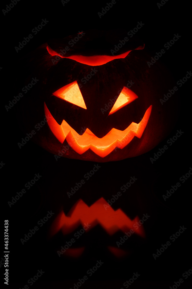 Close up view of scary Halloween pumpkin with eyes glowing inside at black background Close up view of scary Halloween pumpkin with eyes glowing inside at black background