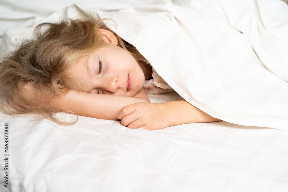 A little blonde is sleeping sweetly in a bed with white underwear. space for the text. healthy sleep of the child A little blonde is sleeping sweetly in a bed with white underwear. space for the text. healthy sleep of the child