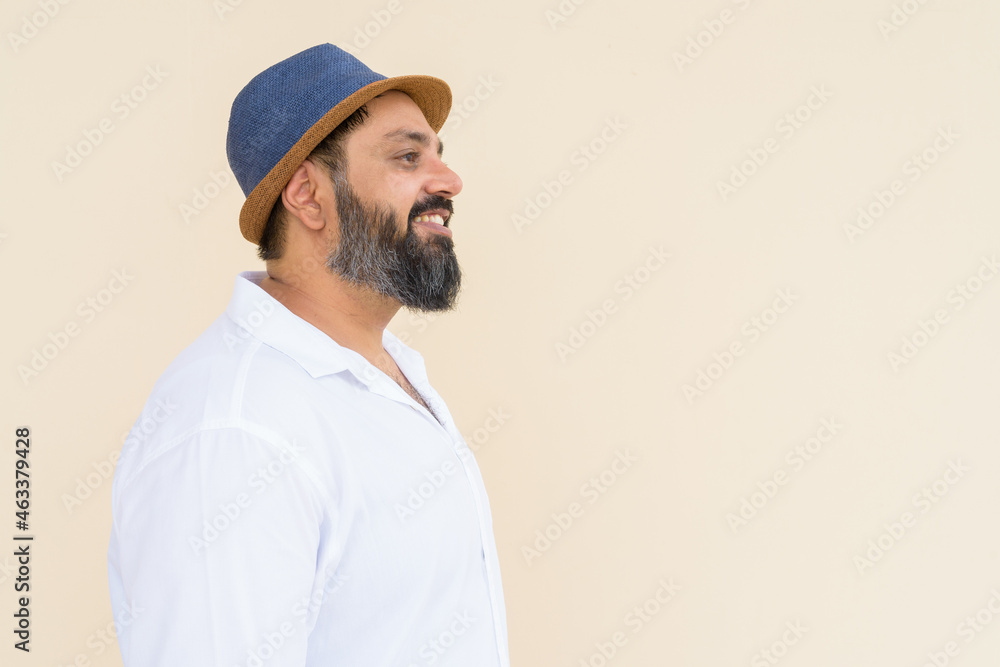 Portrait of handsome bearded Indian man against plain background