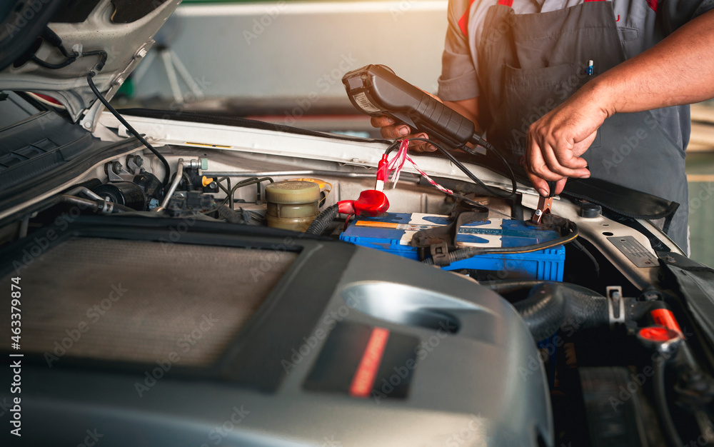 Automobile mechanic repairman hands checking car battery with modern tools digital multimeter in car service center. Automobile mechanic repairman hands checking car battery with modern tools digital multimeter in car service center.