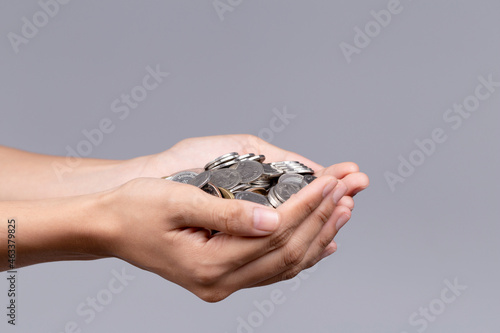 Handful of coins in palm hands isolated on gray background.