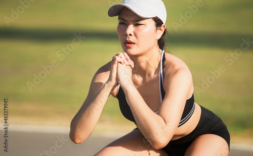 Portrait of healthy young Asian woman exercising in the morning at park. Female fitness working out on sunny day.