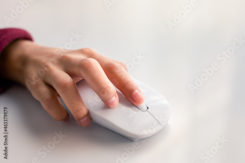 Close-up of woman's hand with computer mouse on white.